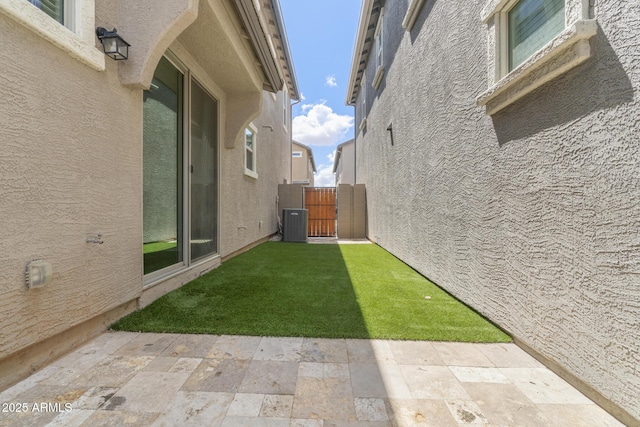 view of green lawn featuring a patio, a gate, and cooling unit