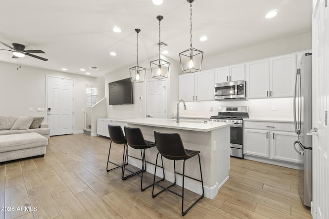 kitchen featuring appliances with stainless steel finishes, a sink, open floor plan, a breakfast bar area, and ceiling fan