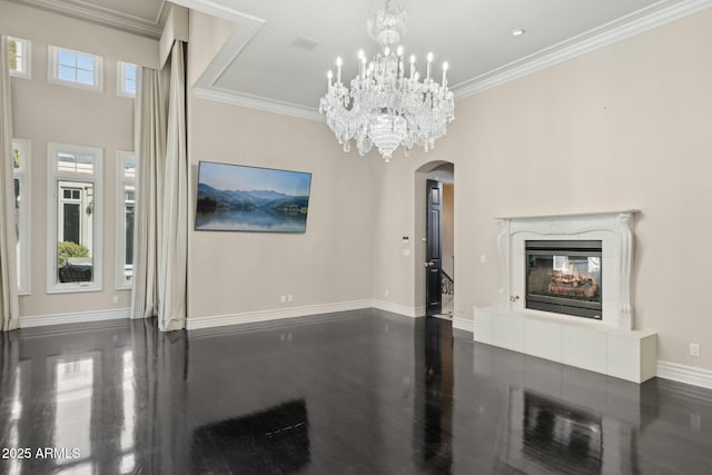 interior space with an inviting chandelier, a high end fireplace, a wealth of natural light, and ornamental molding