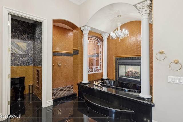 bathroom with a bathtub, ornate columns, and a multi sided fireplace