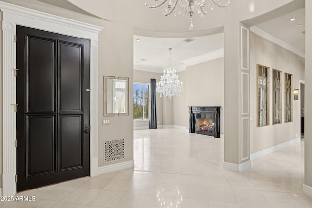 tiled entryway featuring crown molding, a notable chandelier, and a fireplace