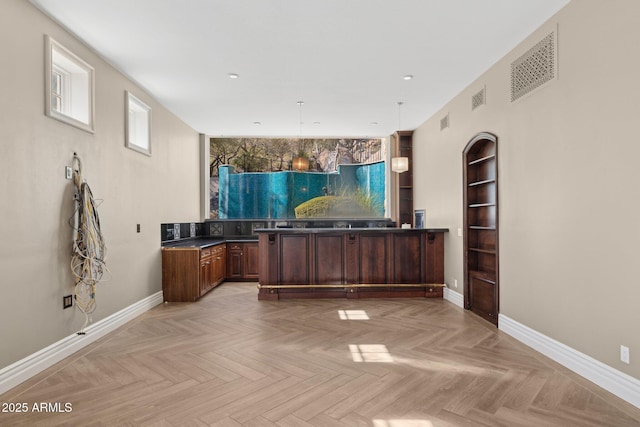 interior space with light parquet floors, built in features, and decorative light fixtures