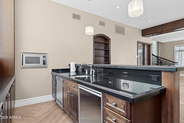 kitchen featuring dark brown cabinetry, sink, stainless steel microwave, white dishwasher, and kitchen peninsula