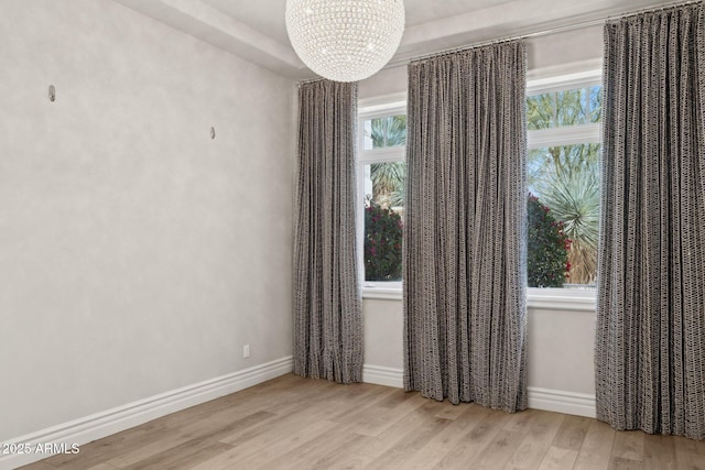 empty room featuring a notable chandelier and light hardwood / wood-style flooring