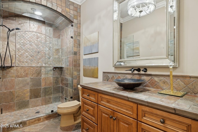 bathroom with crown molding, vanity, toilet, and a tile shower