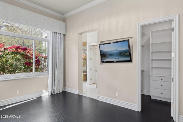 unfurnished bedroom with ornamental molding, a spacious closet, and a closet