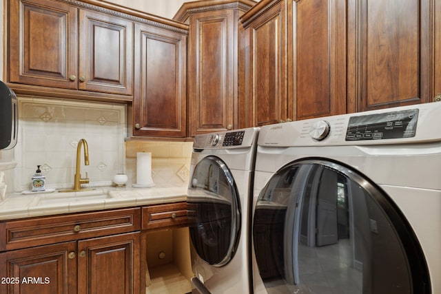 laundry area with cabinets, washing machine and clothes dryer, and sink