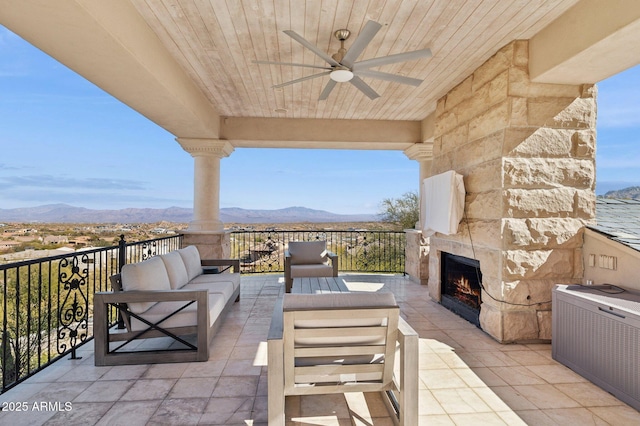 view of patio / terrace with a mountain view, an outdoor living space with a fireplace, and ceiling fan