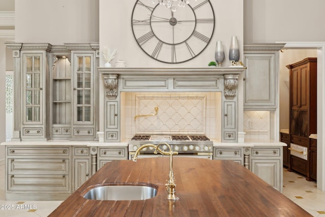 kitchen with stove, sink, backsplash, and wooden counters