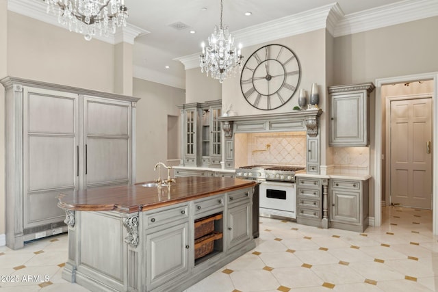 kitchen featuring butcher block countertops, sink, double oven range, a notable chandelier, and crown molding