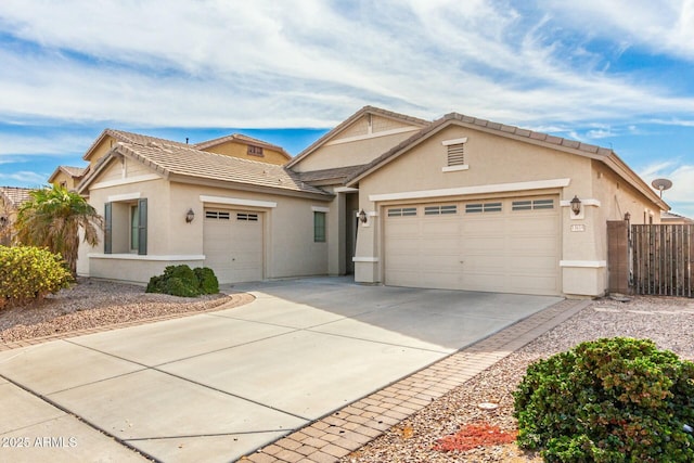 view of front of property featuring fence, driveway, stucco siding, and a garage