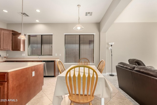 kitchen with light tile patterned floors, visible vents, hanging light fixtures, light countertops, and stainless steel dishwasher