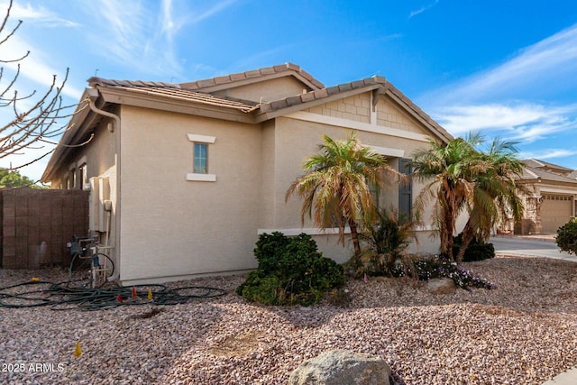 view of side of property featuring a tiled roof, stucco siding, and fence
