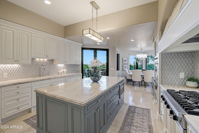 kitchen featuring tasteful backsplash, white cabinetry, sink, and hanging light fixtures