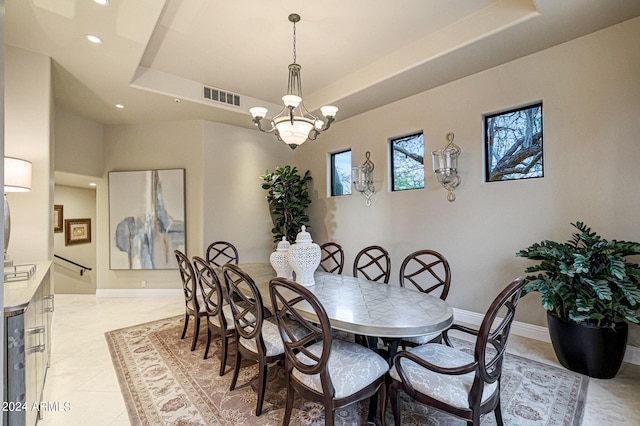 dining space with a tray ceiling, light tile patterned flooring, and a notable chandelier