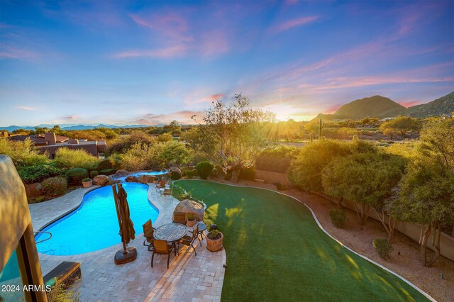 pool at dusk featuring a mountain view and a patio