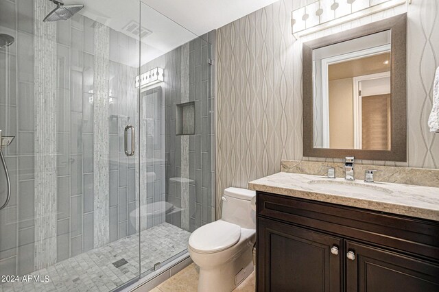 bathroom with vanity, a shower with shower door, tile walls, and toilet