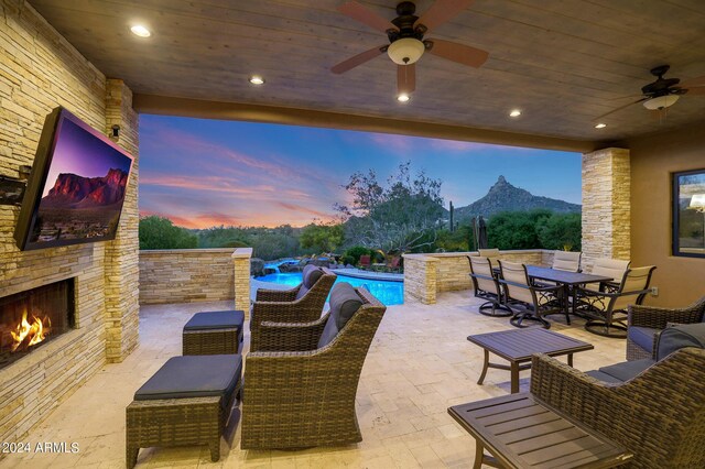 view of patio with an outdoor stone fireplace, ceiling fan, and a mountain view