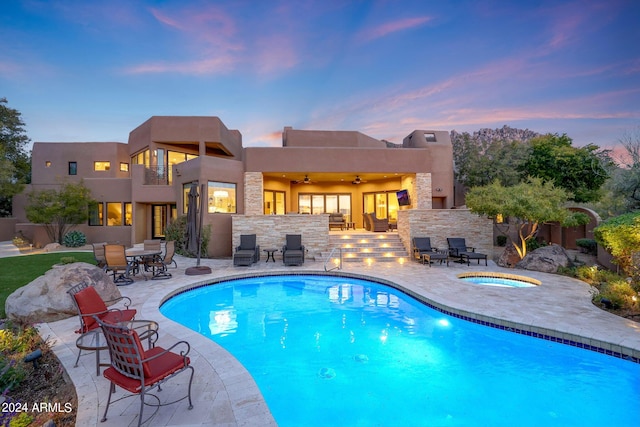 pool at dusk featuring ceiling fan, a patio area, and an in ground hot tub