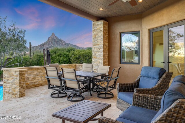 patio terrace at dusk featuring ceiling fan, a mountain view, and an outdoor hangout area