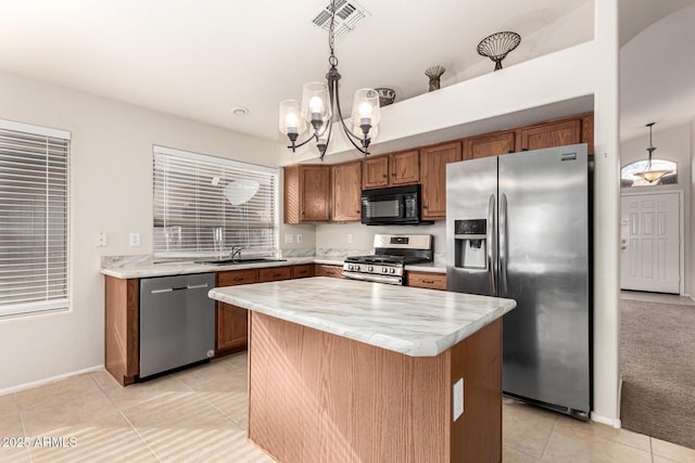 kitchen featuring a sink, visible vents, appliances with stainless steel finishes, a center island, and decorative light fixtures