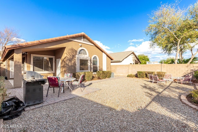 back of house with a tiled roof, a patio area, a fenced backyard, and stucco siding