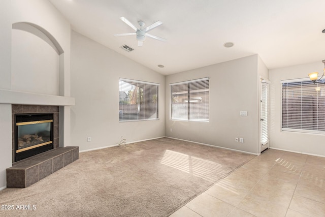 unfurnished living room featuring light carpet, visible vents, a ceiling fan, vaulted ceiling, and a tiled fireplace