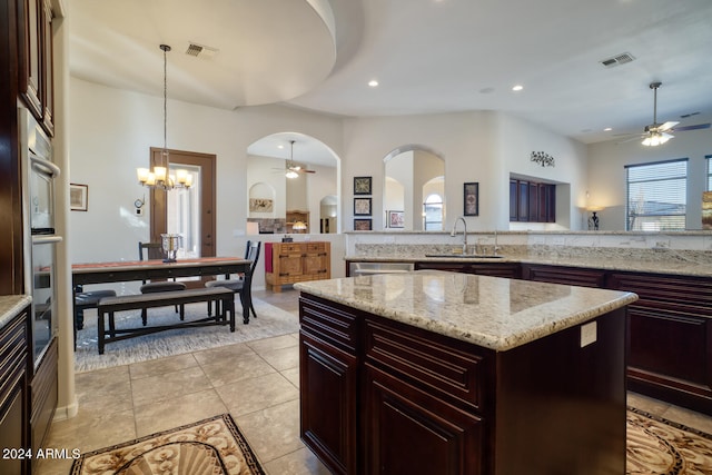 kitchen with a kitchen island, sink, pendant lighting, a chandelier, and appliances with stainless steel finishes