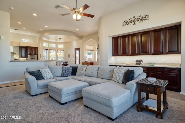 carpeted living room featuring ceiling fan and a towering ceiling