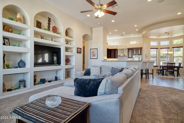 tiled living room with ceiling fan with notable chandelier and built in features