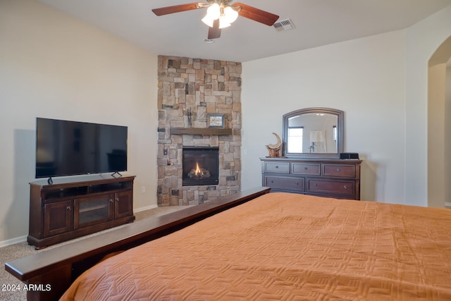 bedroom featuring ceiling fan and a stone fireplace