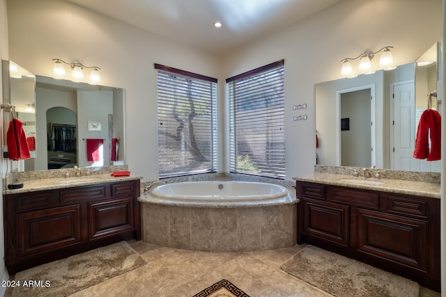 bathroom featuring tile patterned flooring, tiled bath, and vanity