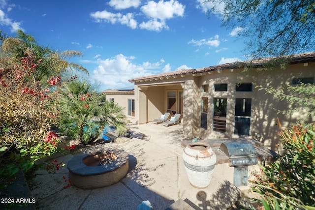 back of house featuring a fire pit, area for grilling, and a patio