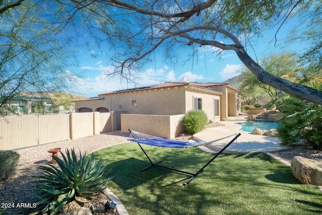 rear view of house featuring a fenced in pool and a lawn