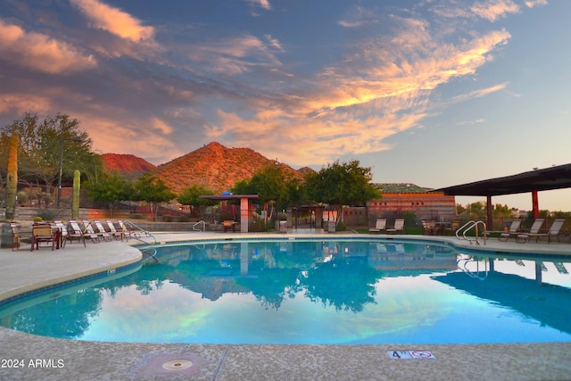 pool at dusk featuring a mountain view and a patio area