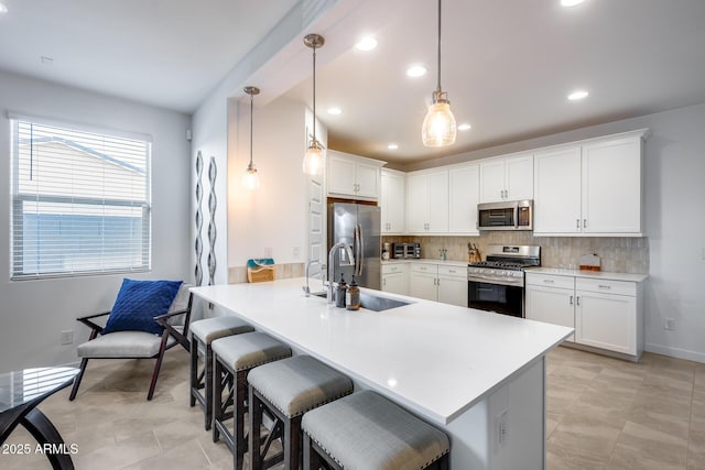 kitchen featuring stainless steel appliances, sink, white cabinetry, a kitchen bar, and pendant lighting