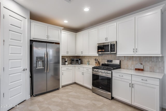 kitchen with stainless steel appliances, white cabinets, and backsplash