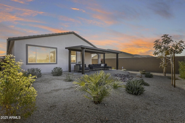 back house at dusk with a patio area and outdoor lounge area