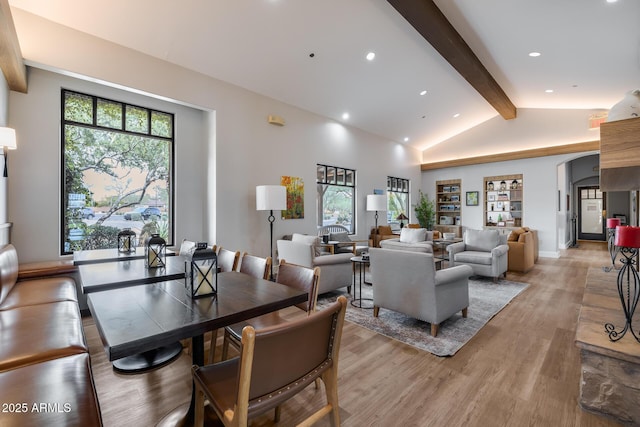 living room featuring a healthy amount of sunlight, light hardwood / wood-style flooring, high vaulted ceiling, and beamed ceiling