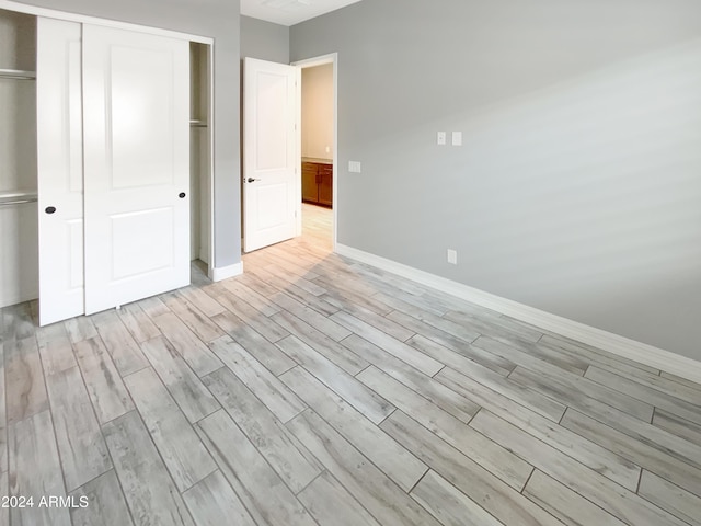 unfurnished bedroom with light hardwood / wood-style flooring and a closet