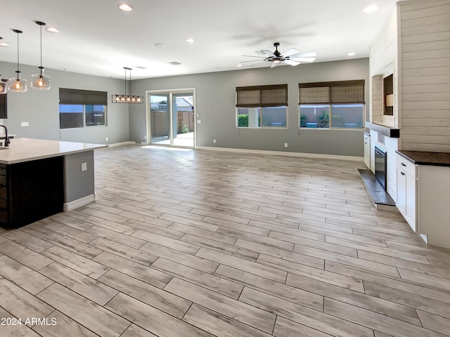 kitchen featuring ceiling fan, white cabinetry, hanging light fixtures, and light hardwood / wood-style flooring