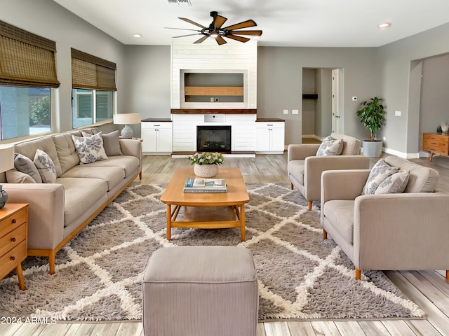 living room with ceiling fan, a fireplace, and light hardwood / wood-style floors