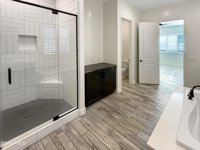 bathroom with wood-type flooring, toilet, and walk in shower