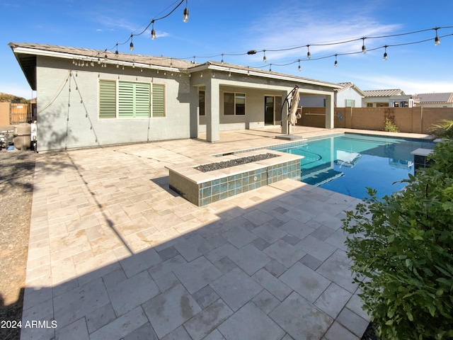 rear view of property featuring a fenced in pool and a patio