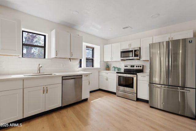 599 W Vah Ki Inn Rd, Coolidge, AZ 85128 - kitchen with appliances with stainless steel finishes, a sink, tasteful backsplash, light wood finished floors, and white cabinets