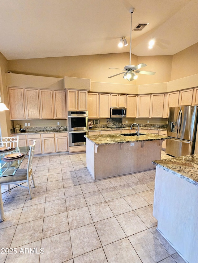 kitchen featuring light stone countertops, sink, stainless steel appliances, and a breakfast bar