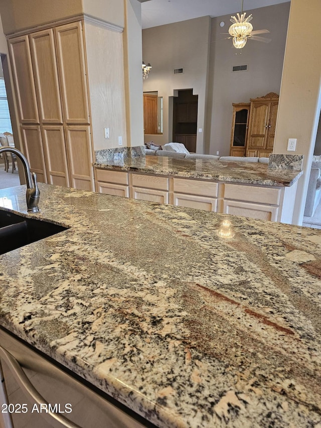 kitchen with ceiling fan, a high ceiling, pendant lighting, and light stone counters