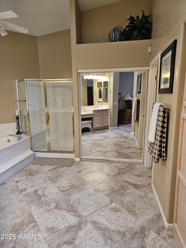 bathroom with ceiling fan, vanity, a towering ceiling, and plus walk in shower