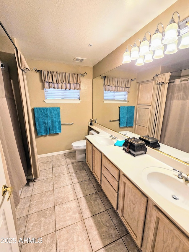 bathroom with a textured ceiling, toilet, vanity, and tile patterned flooring