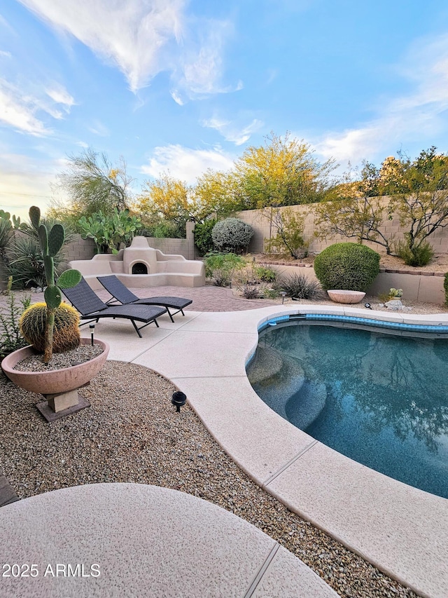 view of swimming pool featuring an outdoor fireplace and a patio area